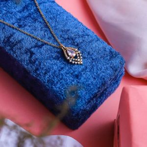 An Elegant Gold Necklace With A Luxurious Design, Featuring A Radiant Colored Gemstone Surrounded By Sparkling Diamonds