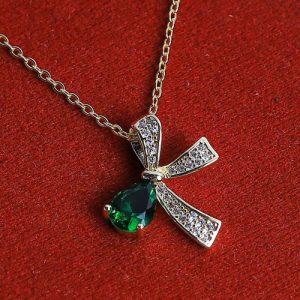 A Golden Necklace With A Captivating Bow Design, Featuring A Vibrant Oval-shaped Gemstone At Its Center