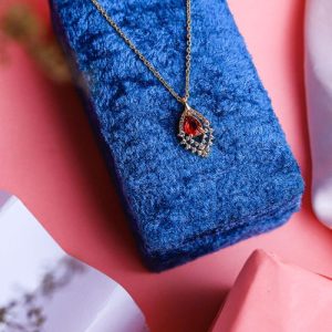 An Elegant Gold Necklace With A Luxurious Design, Featuring A Radiant Colored Gemstone Surrounded By Sparkling Diamonds
