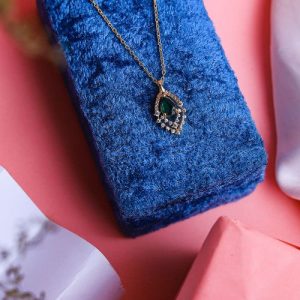 An Elegant Gold Necklace With A Luxurious Design, Featuring A Radiant Colored Gemstone Surrounded By Sparkling Diamonds